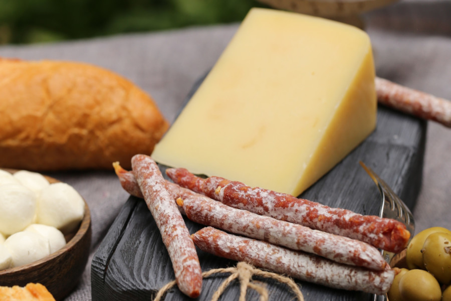 Käseplatte mit Salamistangen, Brot und Oliven.