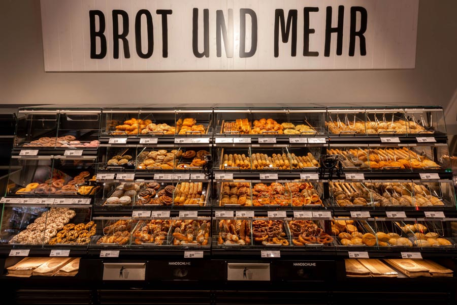 Große Selbstbedienungs-Backwarentheke unter dem Schild „BROT UND MEHR“.